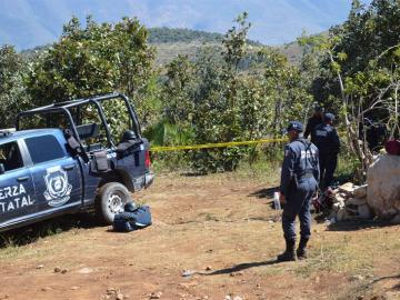 Policías de la Fuerza Estatal resguardan el sitio donde peritos forenses trabajan sobre el hallazgo