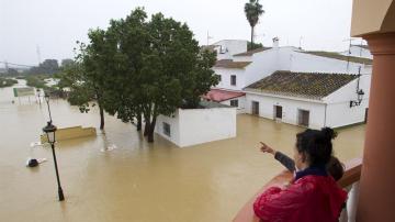 Varias personas observan el estado de sus casas inundadas en la barriada Doña Ana de la localidad de Cártama por las fuertes lluvia caídas esta noche