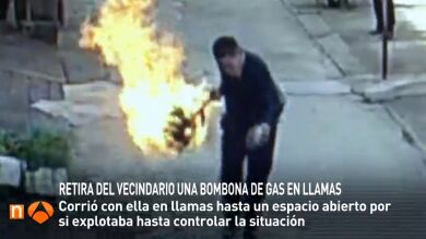 Un hombre aleja una bombona de gas en llamas para evitar una explosión en el vecindario