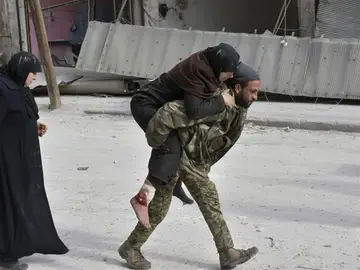 Un soldado sirio trasladando a una mujer herida en Alepo Un soldado sirio trasladando a una mujer herida en Alepo