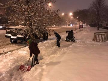 Imagen de los niños ayudando al hombre en silla de ruedas a retirar la nieve