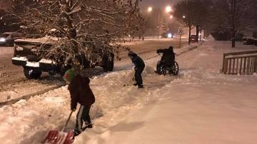 Imagen de los niños ayudando al hombre en silla de ruedas a retirar la nieve