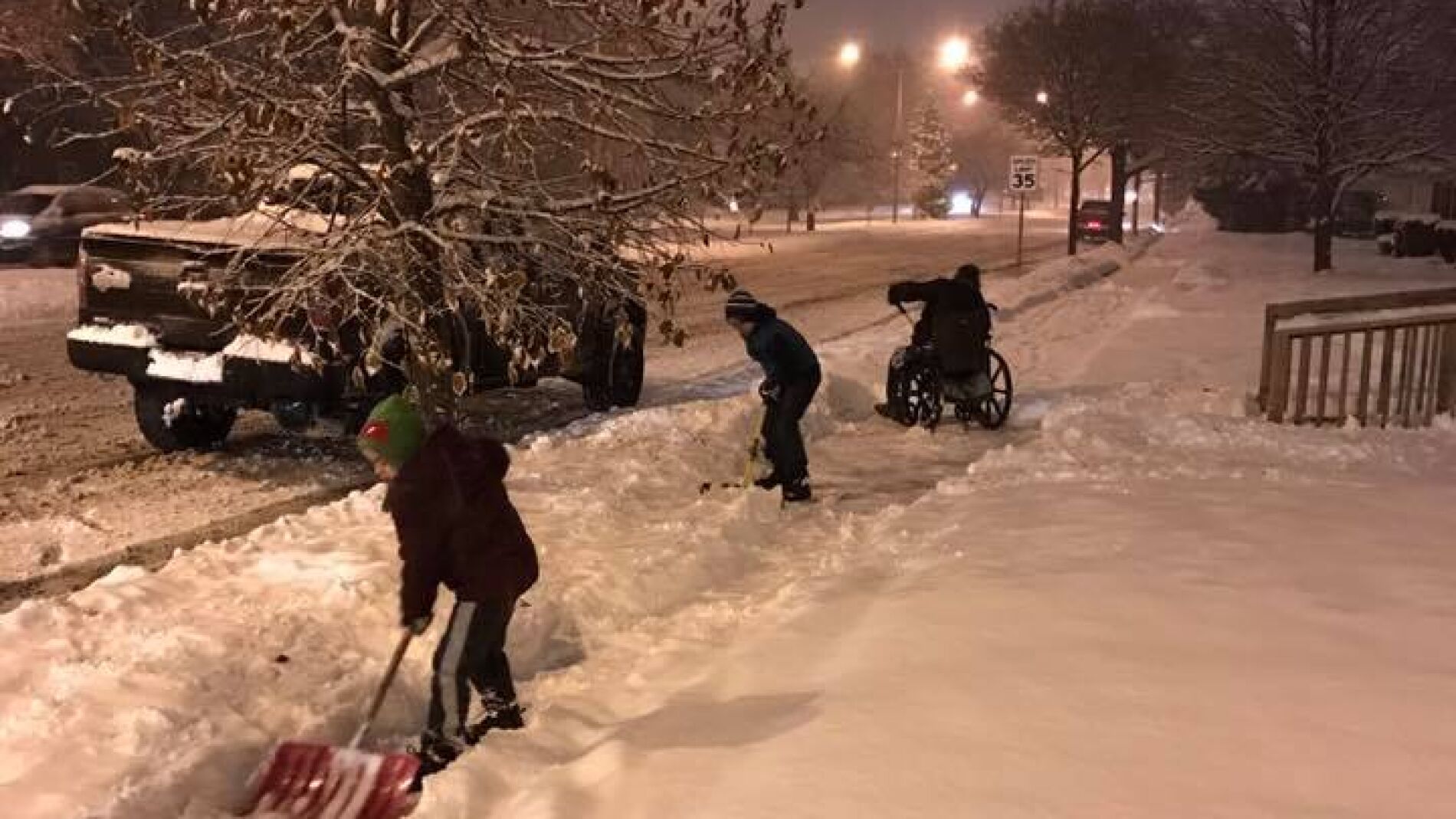 Imagen de los ni&ntilde;os ayudando al hombre en silla de ruedas a retirar la nieve