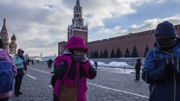 Turistas se abrigan con bufandas durante una visita a la Plaza Roja de Moscú
