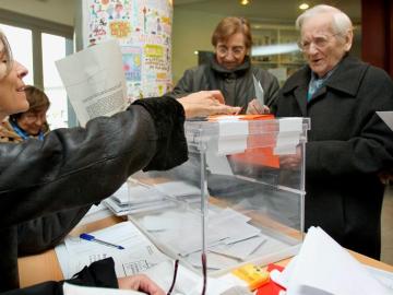 Un hombre deposita su papeleta en la urna de una de las mesas instaladas en un colegio electoral del barrio del eixample barcelonés