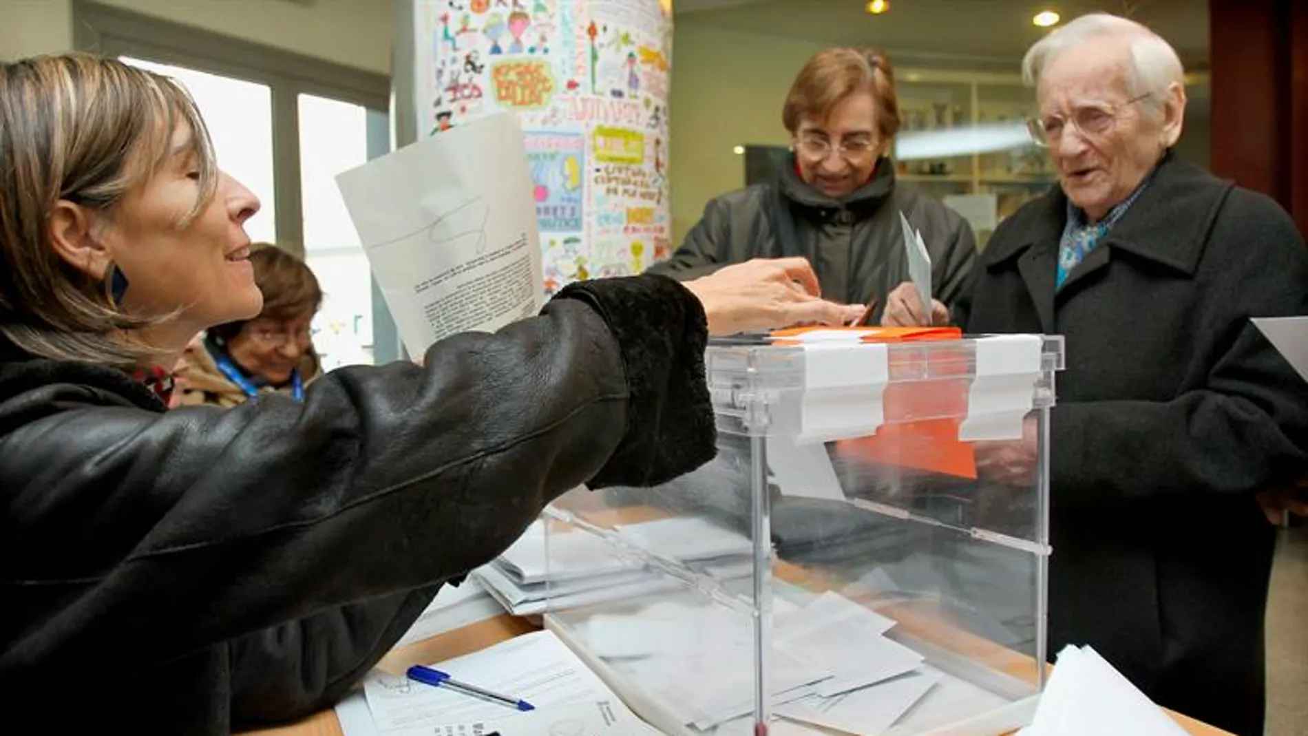 Un hombre deposita su papeleta en la urna de una de las mesas instaladas en un colegio electoral del barrio del eixample barcelonés