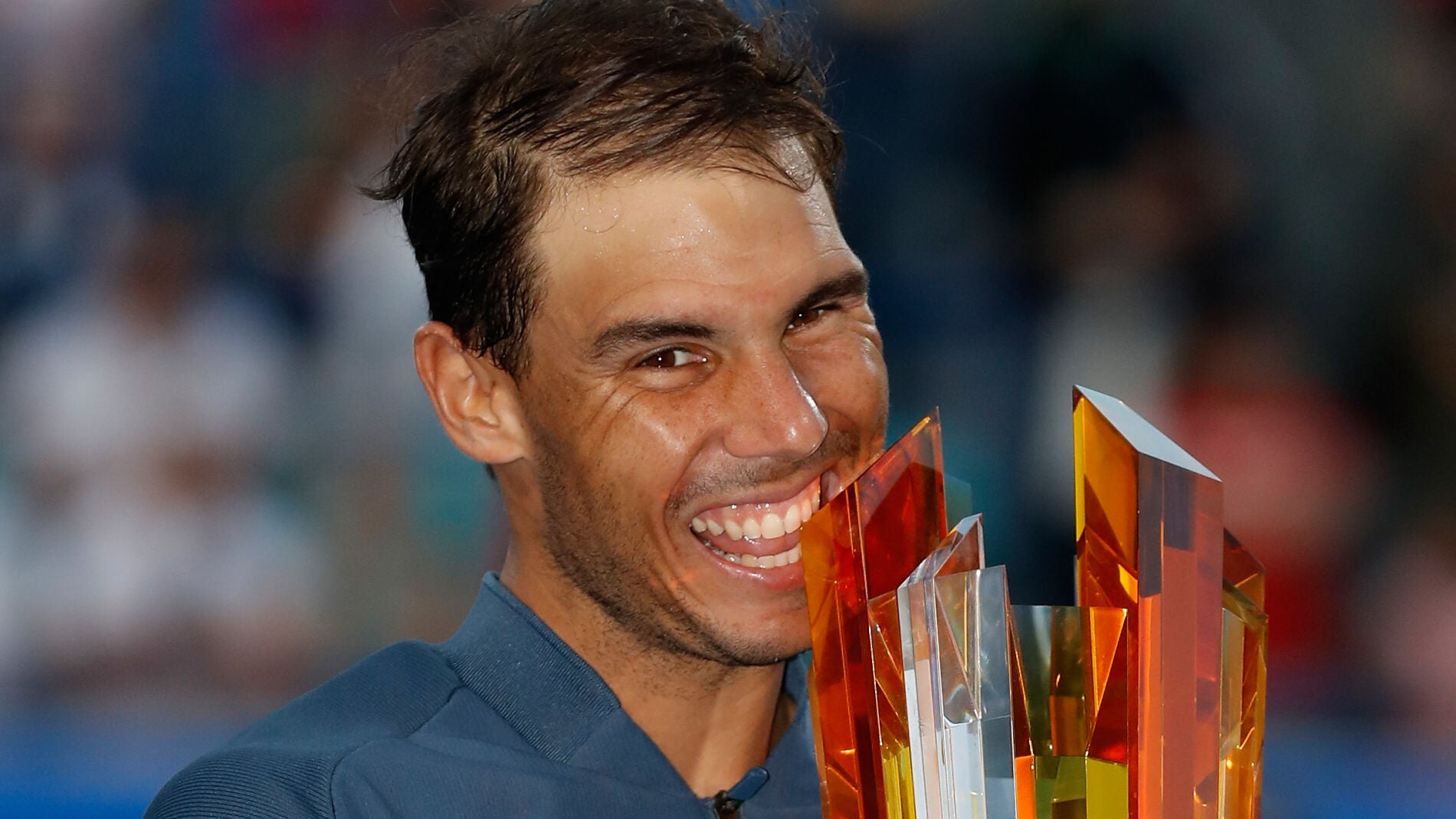 Rafa Nadal muerde el trofeo de campe&oacute;n de Abu Dabi