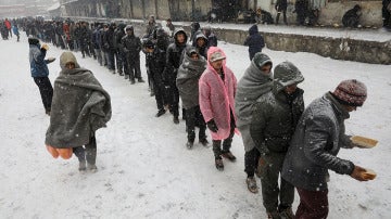 Los refugiados guardan colas por un plato de comida caliente