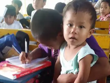 Un niño filipino de nueve años con su hermano de dos en la escuela Un niño filipino de nueve años con su hermano de dos en la escuela
