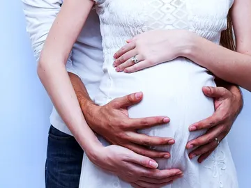 Una pareja abraza la tripa embarazada de la mujer Una pareja abraza la tripa embarazada de la mujer