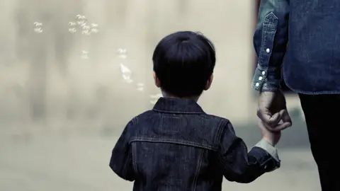 Niño pequeño de la mano Niño, de la mano de su madre