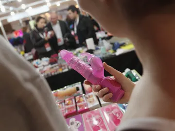 Una mujer cogiendo un juguete erótico en el stand de una feria en Berlín Una mujer cogiendo un juguete erótico en el stand de una feria en Berlín
