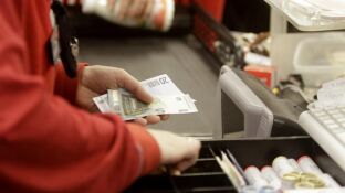 Una cajera de un supermercado devolviendo dinero a un cliente