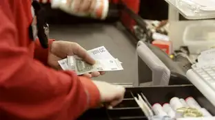 Una cajera de un supermercado devolviendo dinero a un cliente Una cajera de un supermercado devolviendo dinero a un cliente