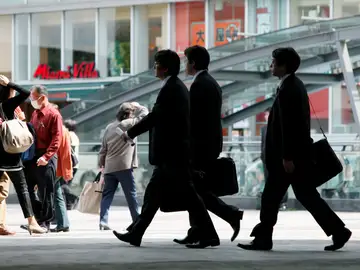 Empresarios caminan por una calle en Tokio (Japón) Empresarios caminan por una calle en Tokio (Japón)