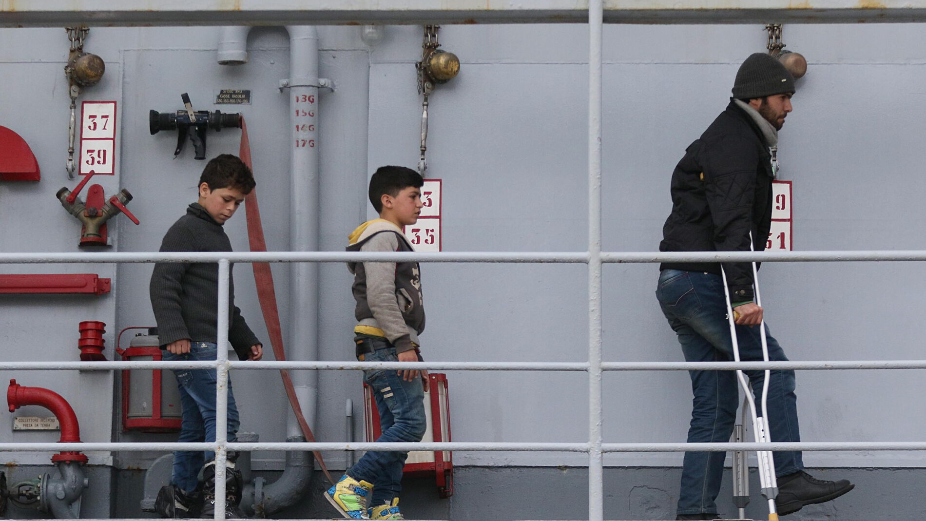 Ni&ntilde;os inmigrantes se disponen a desembarcar en Italia tras ser rescatados en aguas del Mediterr&aacute;neo