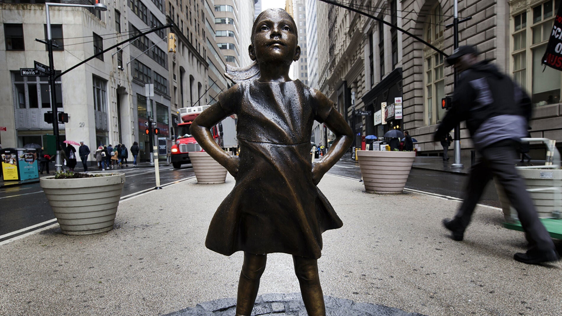 Figura de bronce de una ni&ntilde;a junto al toro de Wall Street