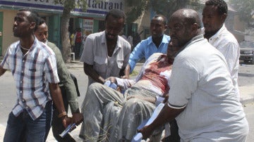 Un grupo de hombres transportan a un herido en la explosión