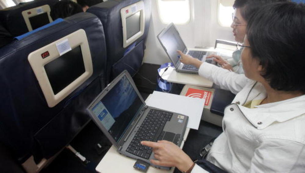 Dos pasajeros utilizando el ordenador portátil en un vuelo