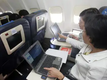 Dos pasajeros utilizando el ordenador portátil en un vuelo Dos pasajeros utilizando el ordenador portátil en un vuelo