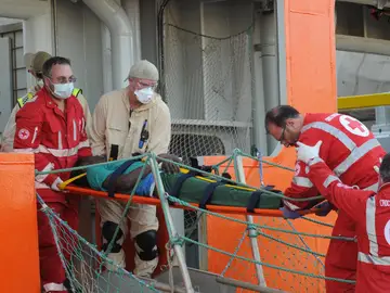 Varios miembros de la Cruz Roja italiana desembarcan a un migrante herido en Palermo, Sicilia Varios miembros de la Cruz Roja italiana desembarcan a un migrante herido en Palermo, Sicilia
