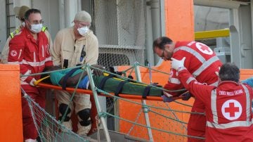 Varios miembros de la Cruz Roja italiana desembarcan a un migrante herido en Palermo, Sicilia 