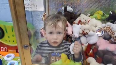 Un niño se introduce en una máquina de juguetes para obtener un peluche