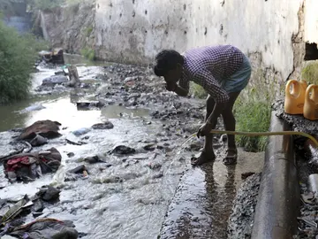 Un hombre bebe agua de una manguera conectada a la fuga de un oleoducto en Nueva Delhi Un hombre bebe agua de una manguera conectada a la fuga de un oleoducto en Nueva Delhi