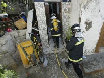 Dos bomberos trabajan en la extinción de un incendio en una casa cueva