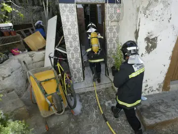 Dos bomberos trabajan en la extinción de un incendio en una casa cueva Dos bomberos trabajan en la extinción de un incendio en una casa cueva