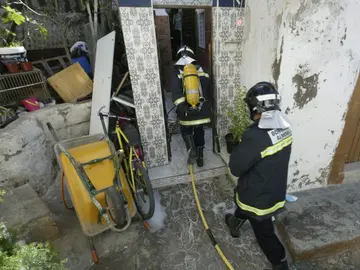 Dos bomberos trabajan en la extinción de un incendio en una casa cueva Dos bomberos trabajan en la extinción de un incendio en una casa cueva