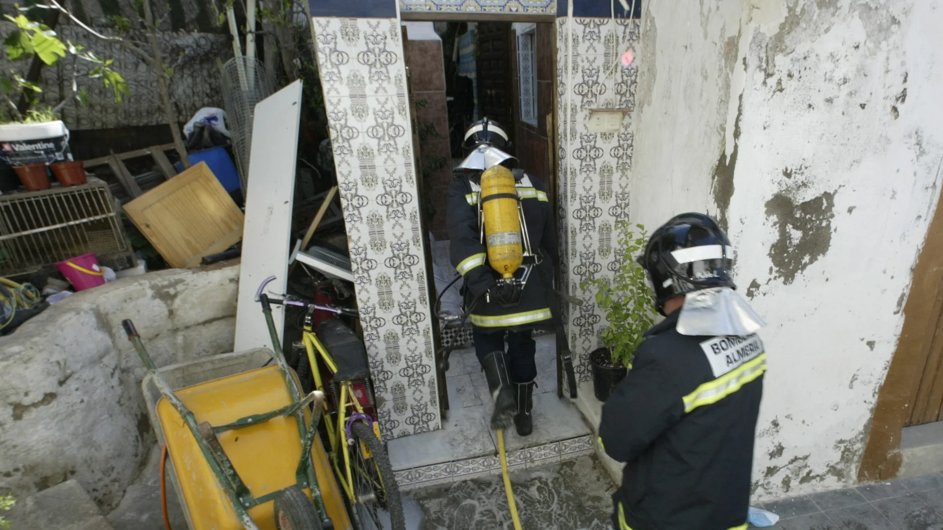 Dos bomberos trabajan en la extinción de un incendio en una casa cueva Dos bomberos trabajan en la extinción de un incendio en una casa cueva