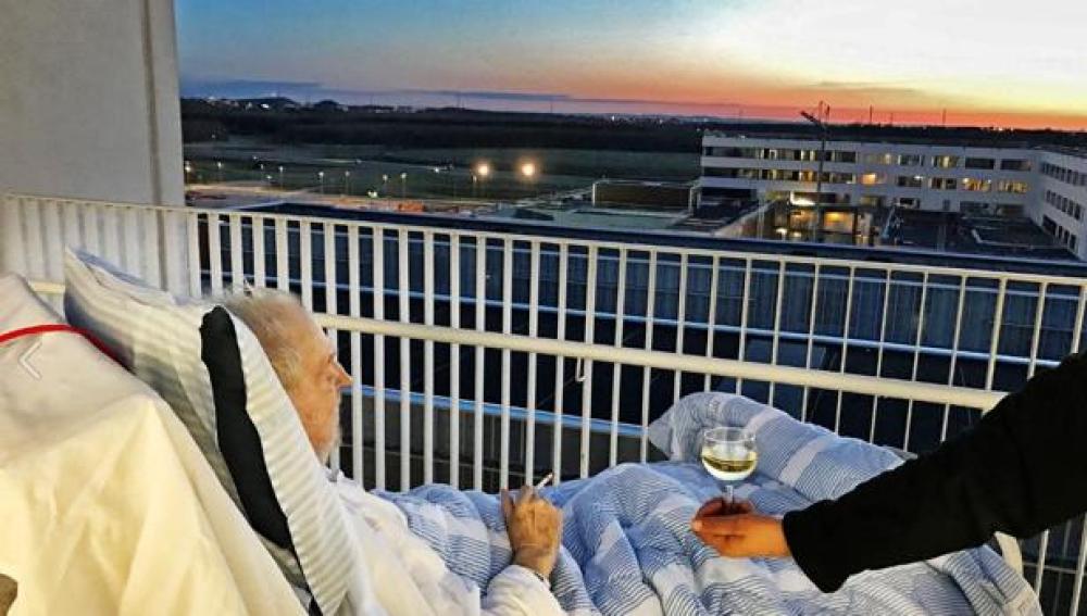 Anciano disfuta de una copa de vino y un cigarro