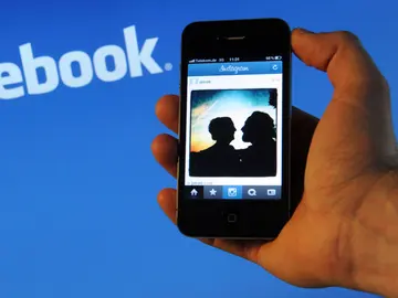 Un iPhone 4 frente al logo de Facebook en un ordenador Un iPhone 4 frente al logo de Facebook en un ordenador