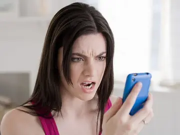 Mujer mirando el móvil enfadada Mujer mirando el móvil enfadada