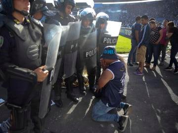 Un aficionado se arrodilla ante la policía en Honduras