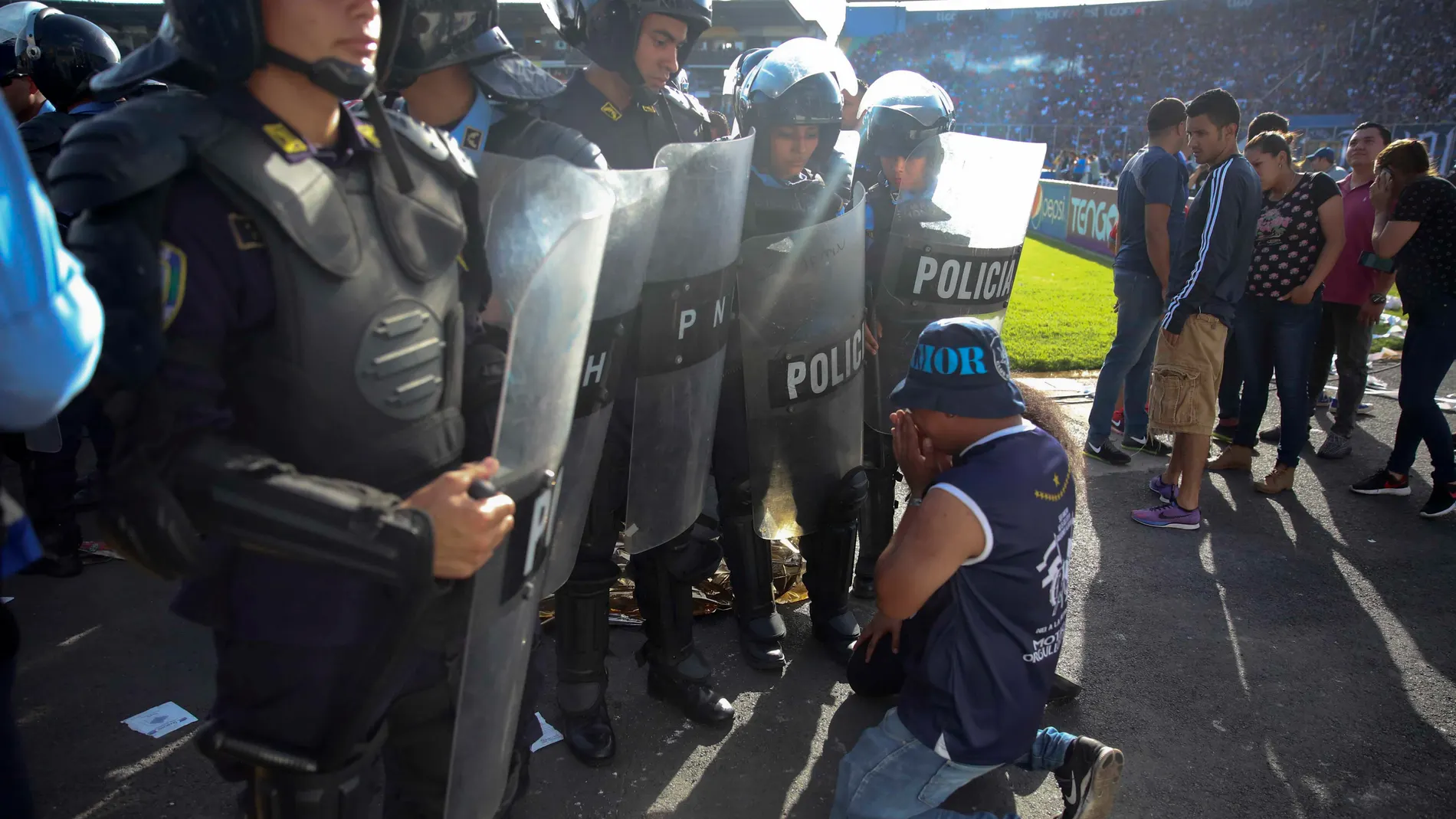 Un aficionado se arrodilla ante la policía en Honduras Un aficionado se arrodilla ante la policía en Honduras