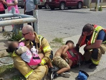 Bomberos consolando a dos niños después de un accidente.