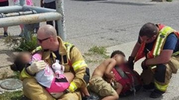 Bomberos consolando a dos niños después de un accidente.