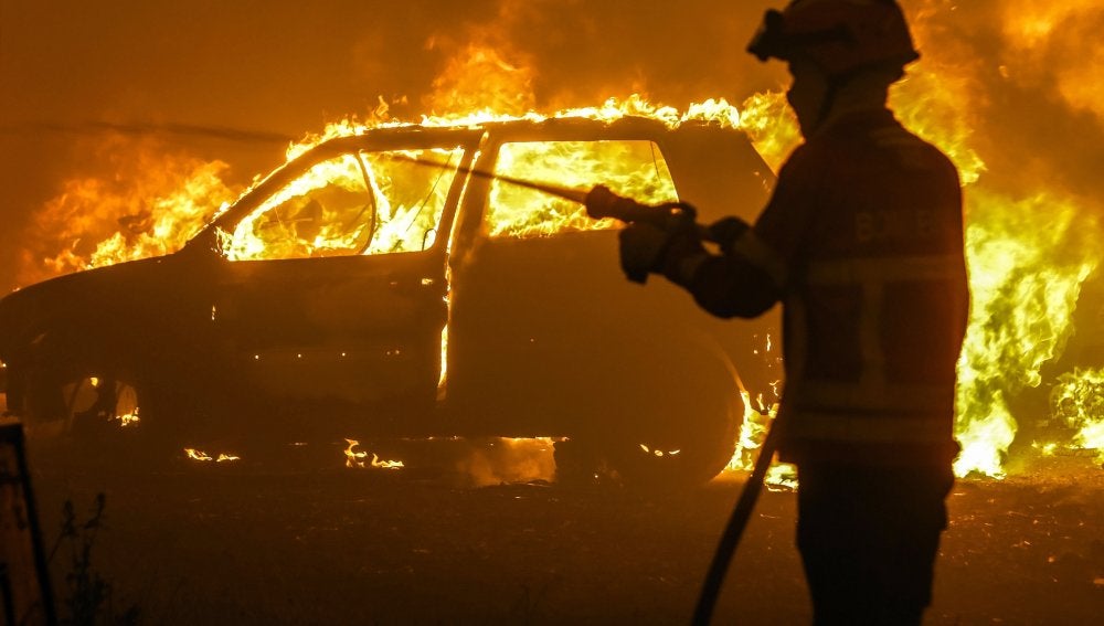 Un bombero intenta sofocar las llamas de uno de los coches atrapados en Portugal