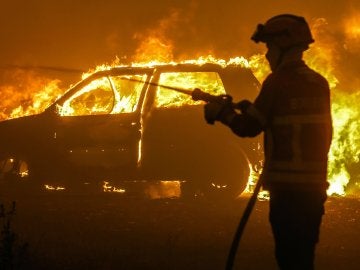 Un bombero intenta sofocar las llamas de uno de los coches atrapados en Portugal