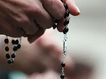 Una mujer con un rosario en la mano Una mujer con un rosario en la mano