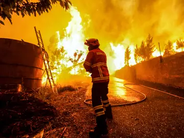 Un bombero intenta sofocar las llamas Un bombero intenta sofocar las llamas