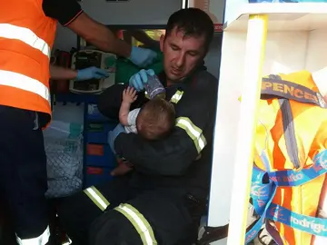 El bombero dando el biberón al bebé El bombero dando el biberón al bebé