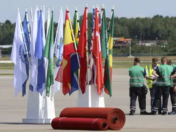 Unos operarios esperan junto a banderas y alfombras rojas preparadas en el aeropuerto para la llegada de los líderes Unos operarios esperan junto a banderas y alfombras rojas preparadas en el aeropuerto para la llegada de los líderes