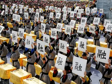 Varias personas sujetan un papel con letras chinas Varias personas sujetan un papel con letras chinas