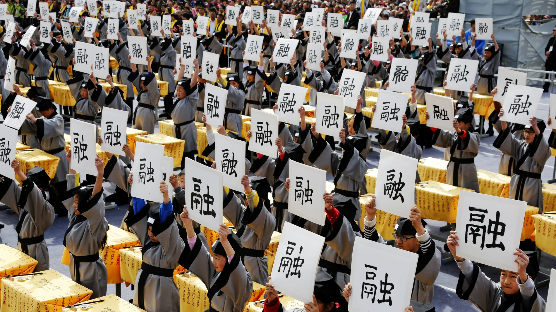 Varias personas sujetan un papel con letras chinas Varias personas sujetan un papel con letras chinas