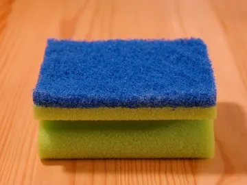 Imagen de un estropajo de cocina apoyado sobre una mesa Imagen de un estropajo de cocina apoyado sobre una mesa