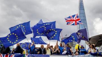 Varias personas con banderas de la Unión Europea protestan contra el brexit en un barco por el río Támesis, en Londres