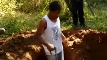 Captura del Jóven cavando, detrás de él un hombre armado